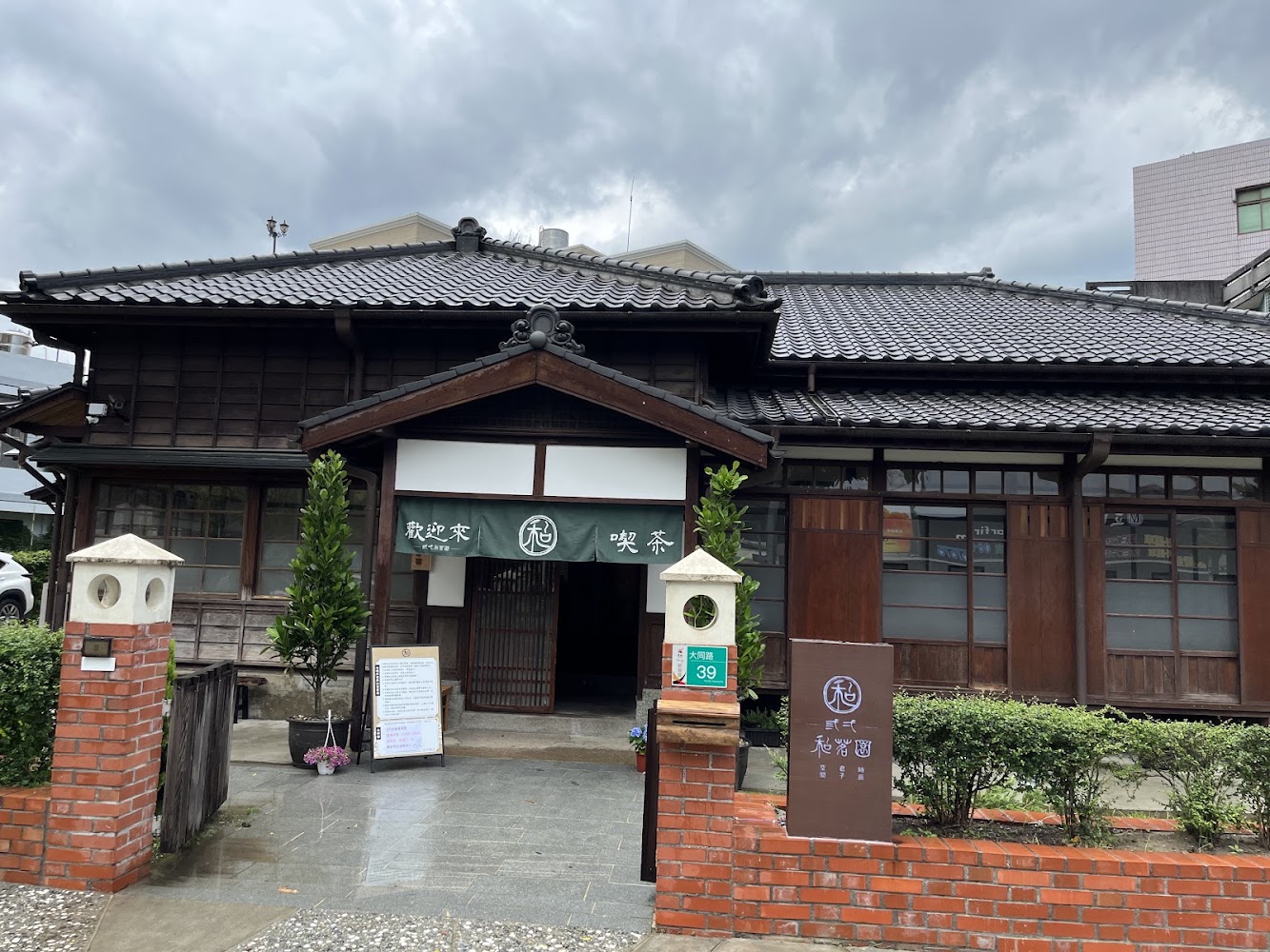 新營縣府日式木造官舍外觀,前方有磚牆與綠植,入口掛有和風布簾