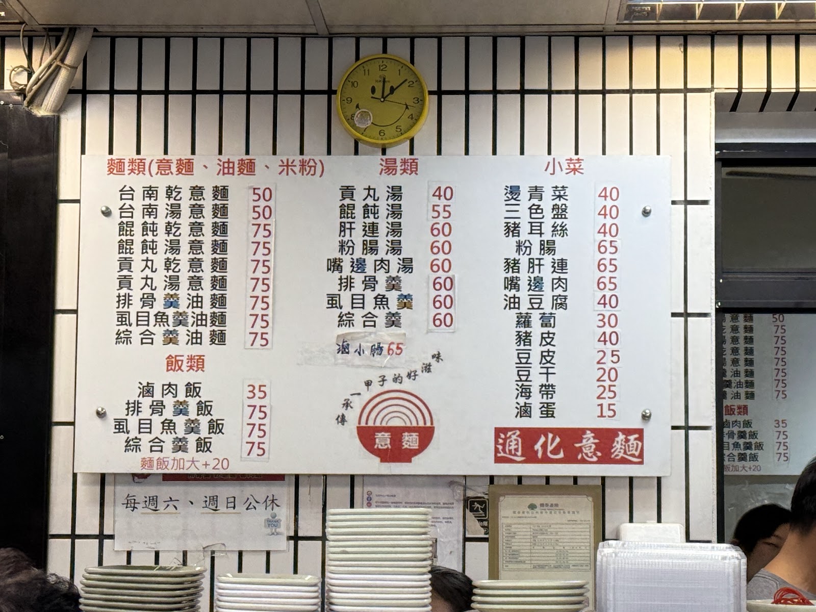 通化意麵店內手寫菜單牆，列出麵類湯類小菜品項與價格，牆上掛著時鐘