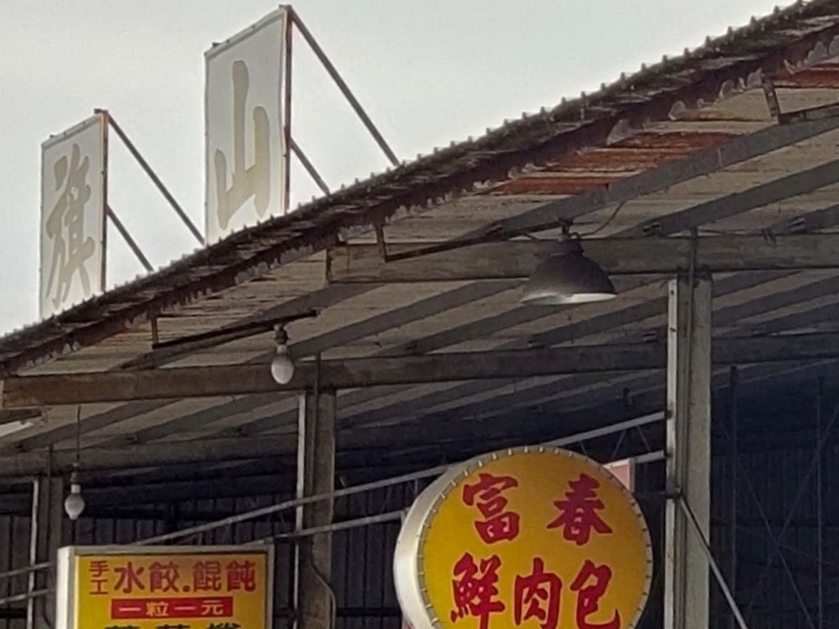 富春鮮肉包圓形招牌懸掛於旗山市場鐵皮棚架下，招牌顯眼