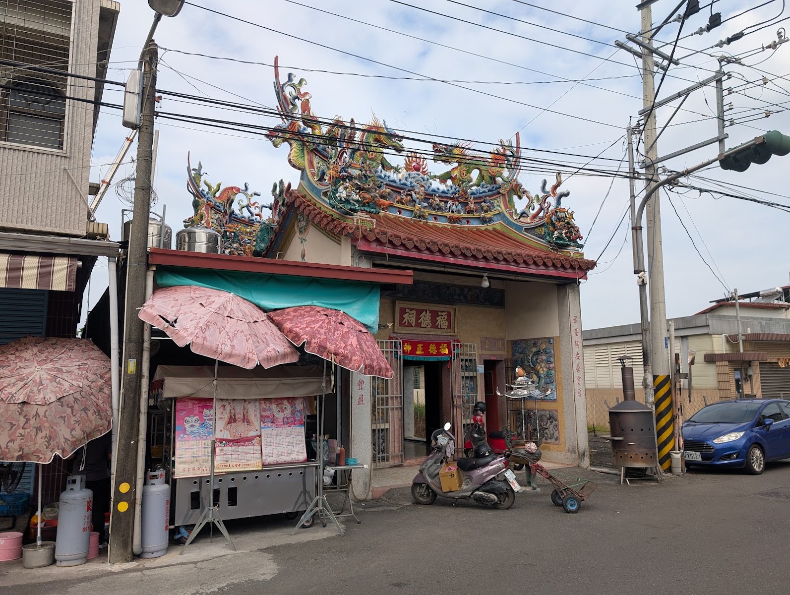 伯公麵店外觀，土地公廟廟埕與紅色遮陽傘