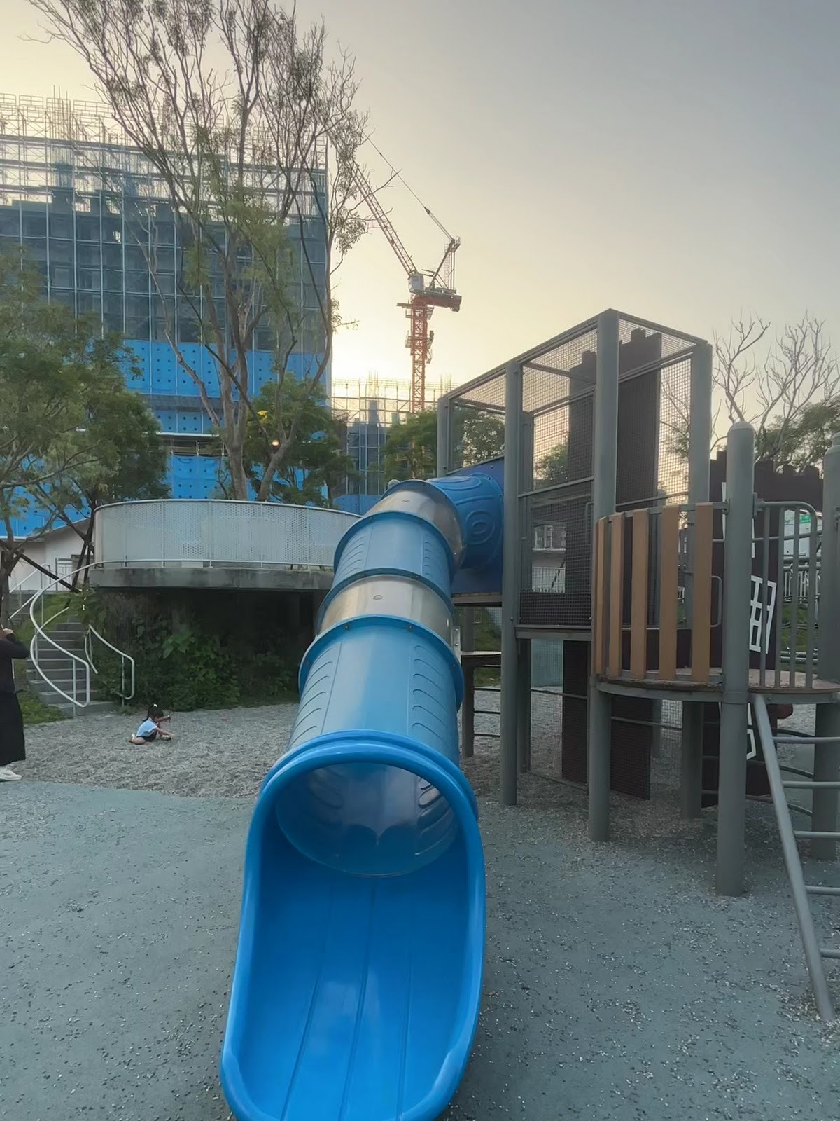福林之丘公園藍色隧道溜滑梯，遊具與背景施工中大樓