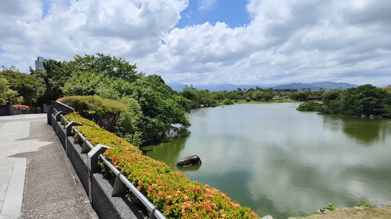 羅東運動公園虹明湖全景遠山雪山藍天白雲花叢欄杆
