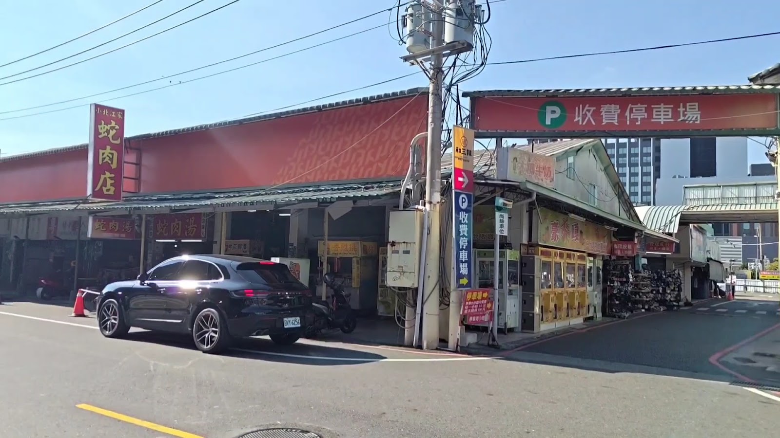 小北觀光夜市白天外觀，紅色鐵皮屋頂店面與收費停車場