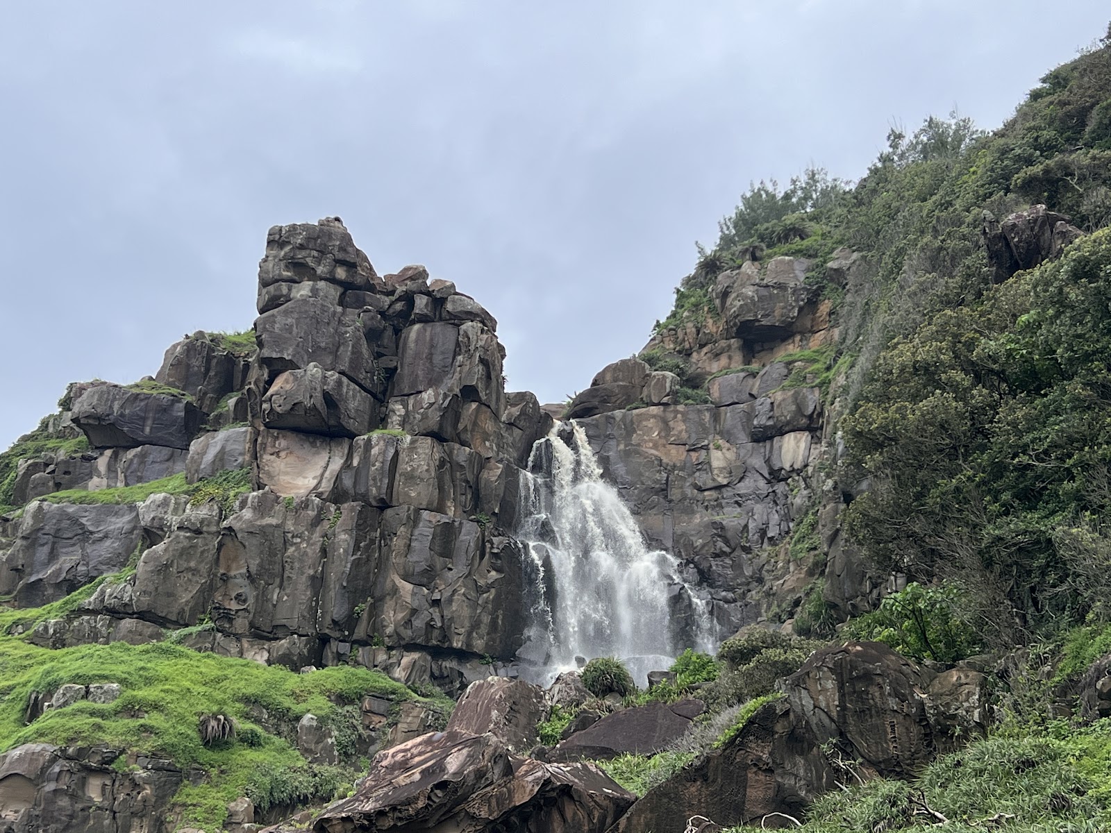 佳樂水山海瀑,岩壁飛瀑從崖頂直落,兩側植被翠綠