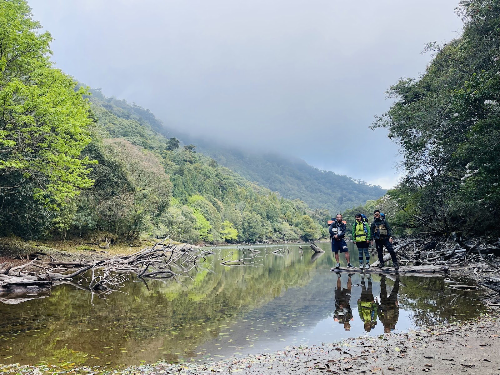 少年溪河道倒影清晰,幾位健行者涉水而過,兩側山壁樹影