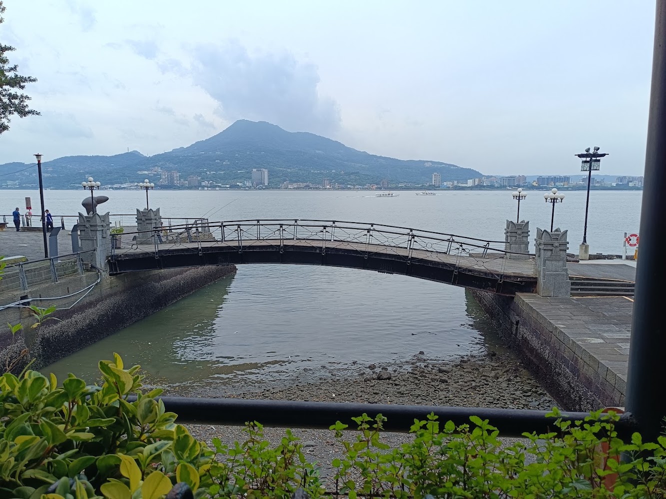 橫跨河流的拱形橋與植物燈柱遠山都市景色