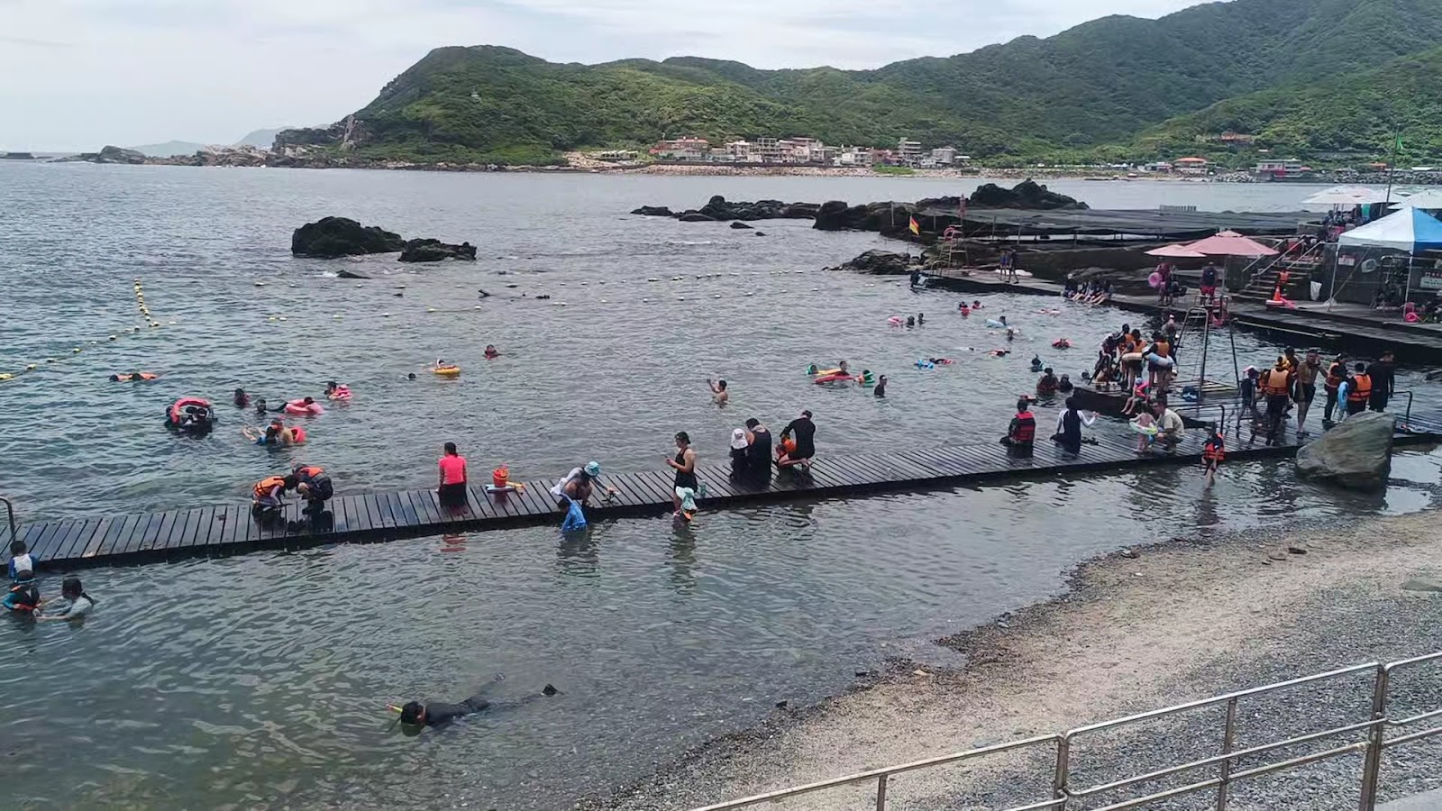 龍洞灣海洋公園假日人潮，浮潛區大批遊客嬉水，木棧道，背景連綿山丘