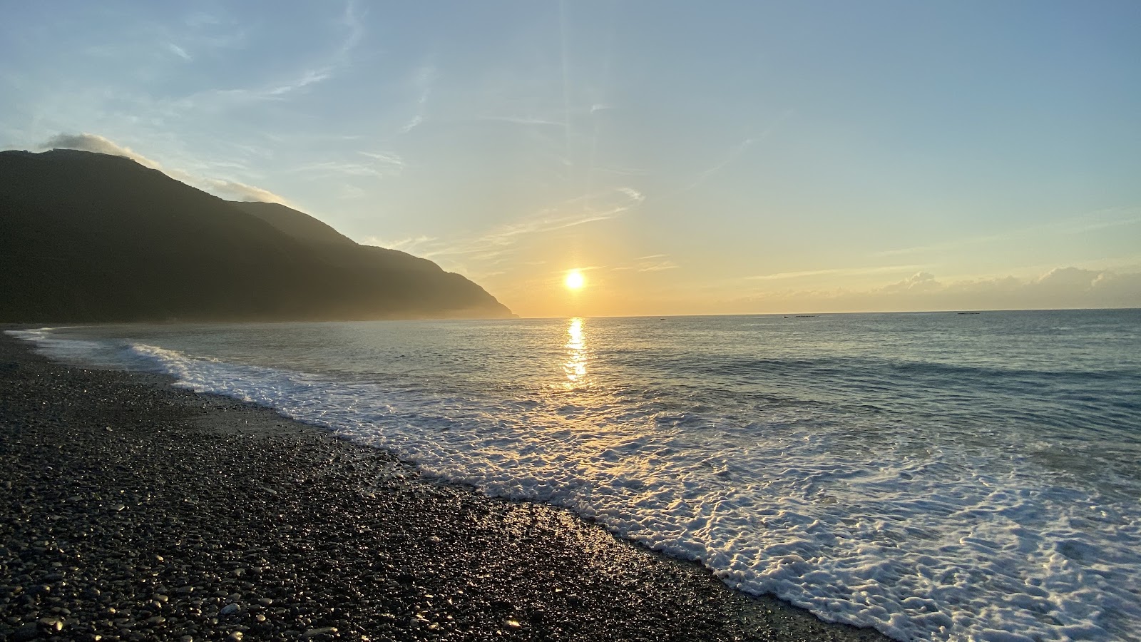 夕陽下的粉鳥林黑色礫石海灘,山脈剪影映入橘紅天際