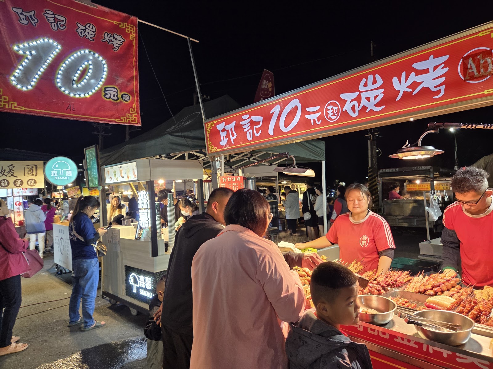 旗山夜市邱記10元起碳烤攤位，紅色招牌燈光下滿滿烤物與排隊人潮