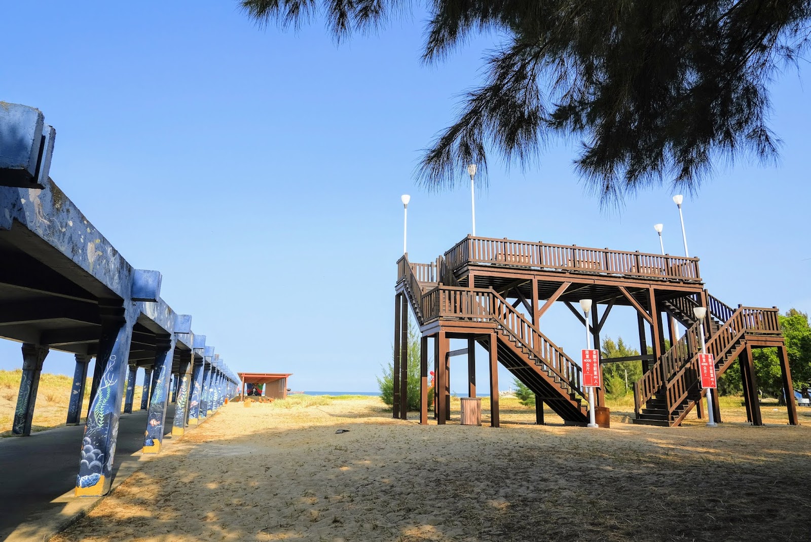 通霄濱海遊憩區木棧觀景平台,藍白欄杆延伸至沙灘,夏日晴空