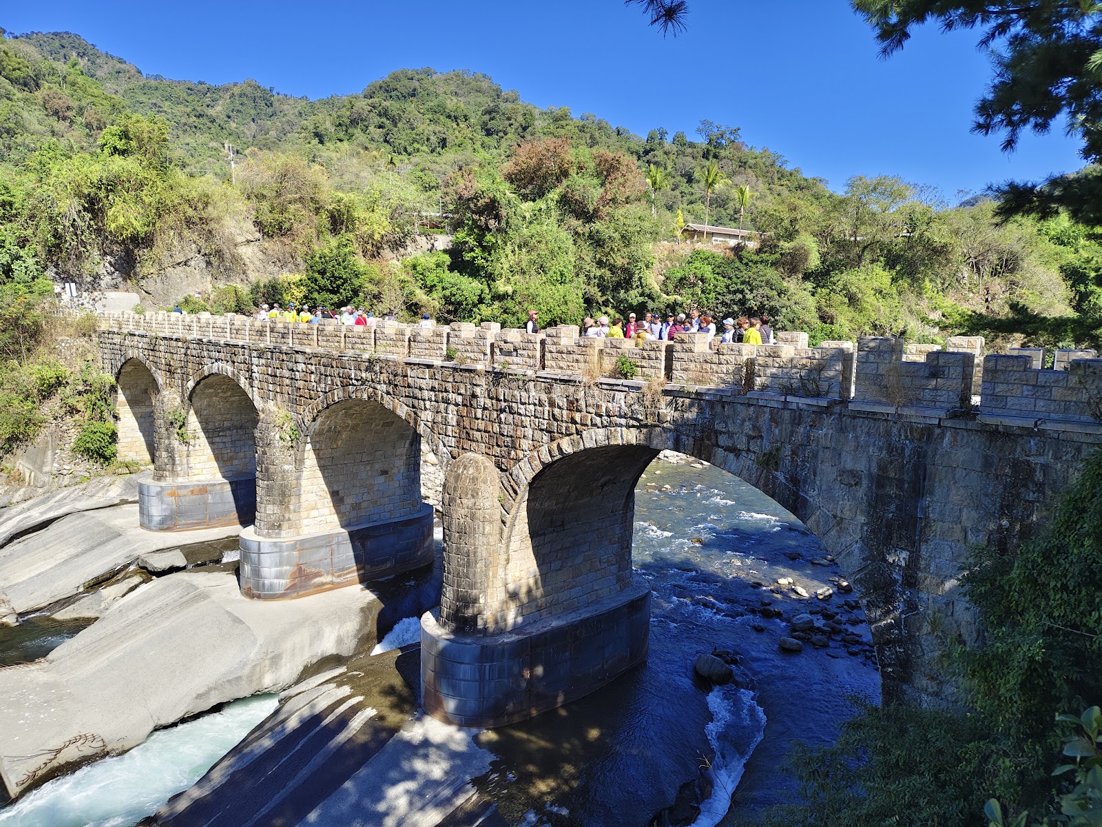 北港溪糯米石橋四孔拱橋全景，遊客列隊走過橋面