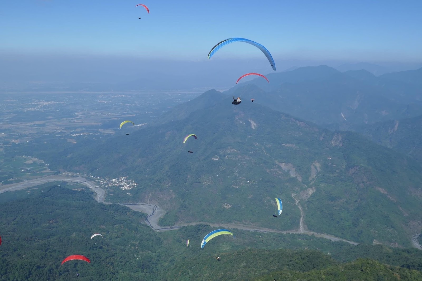 多朵飛行傘同時在三地門山谷上空盤旋,俯瞰底下蜿蜒溪流與農田