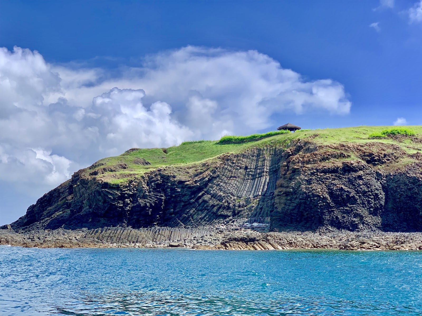 員貝嶼石硯遠景，草綠山丘與藍色海面相映