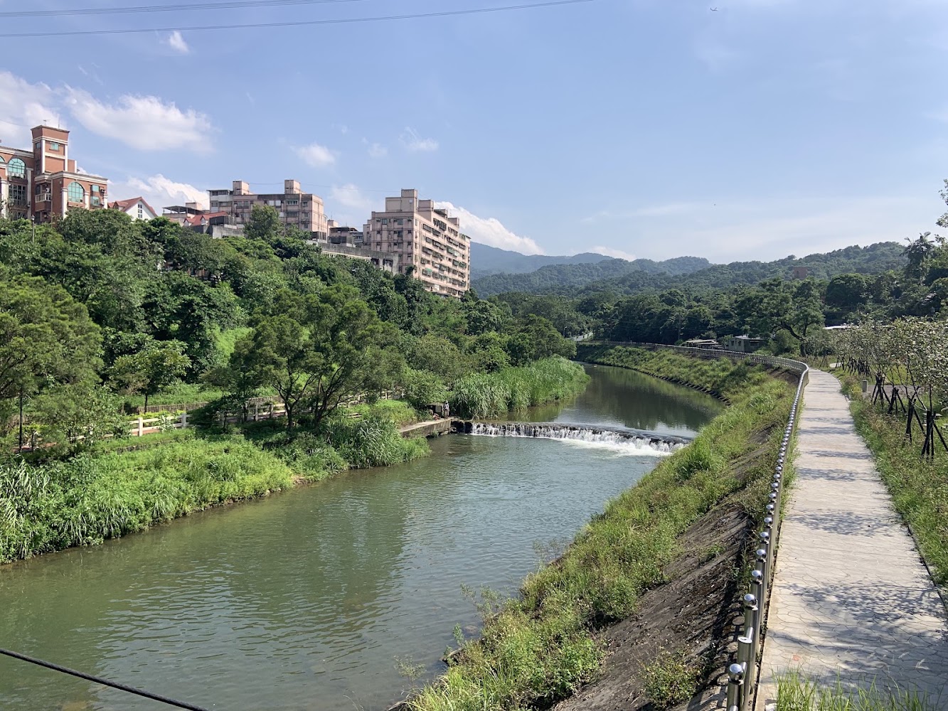 河流與人行步道，河岸兩側綠樹成蔭