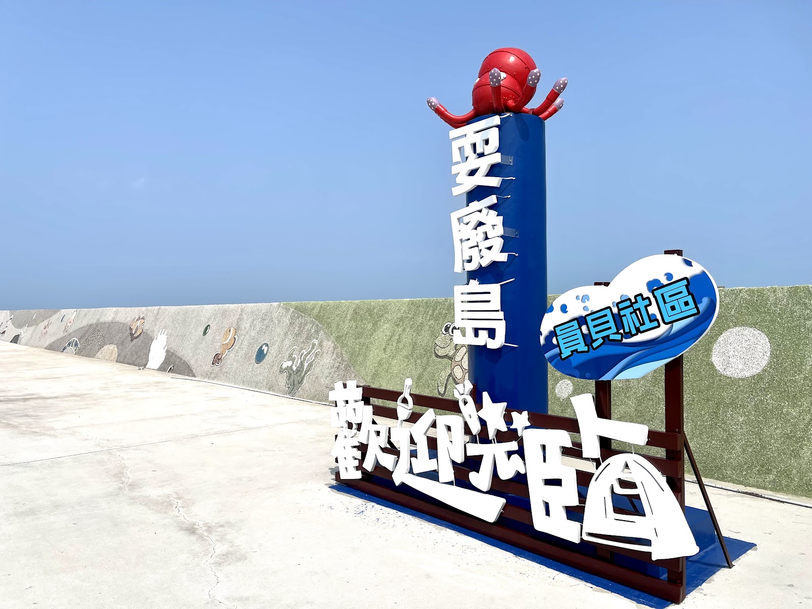 「耍廢島 歡迎光臨」藍白色地標，頂端裝飾一隻紅色章魚
