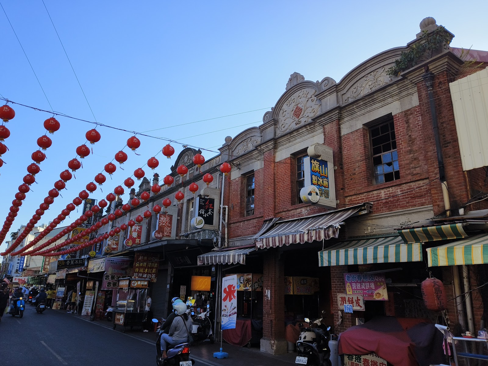 旗山老街巴洛克式紅磚建築街景，紅燈籠高掛，藍天白雲晴朗午後