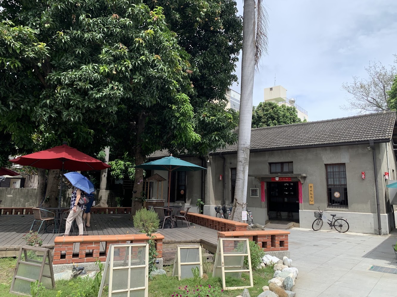 復古建築前庭有桌椅、陽傘與綠樹，氛圍悠閒。
