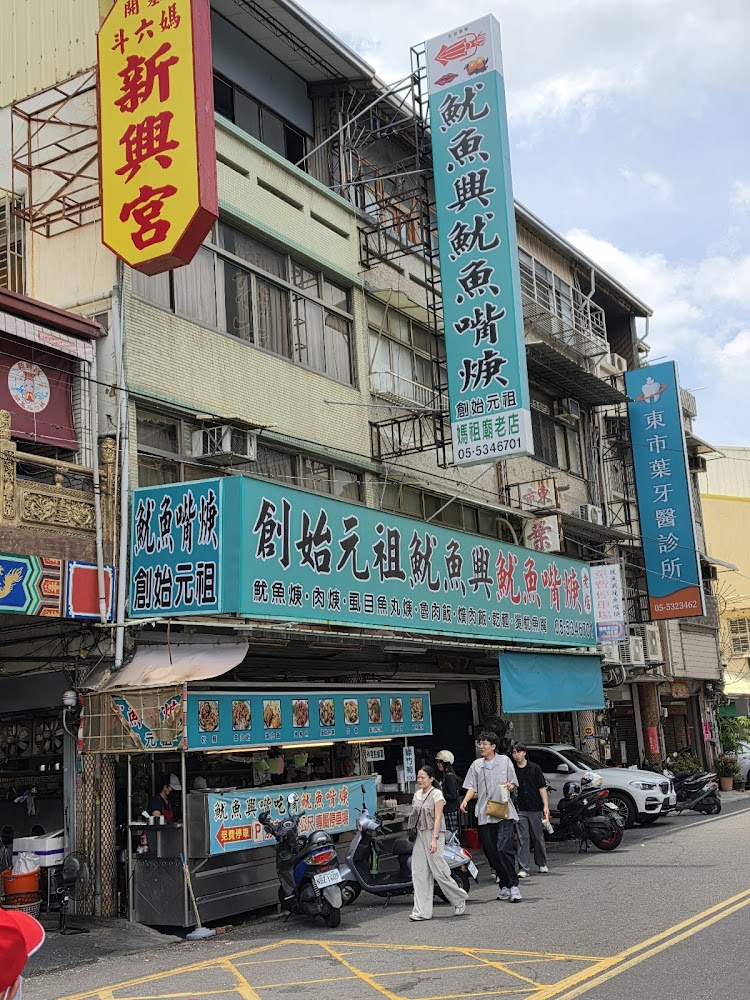 店面外觀有大招牌，顯示魷魚興與創始字樣。