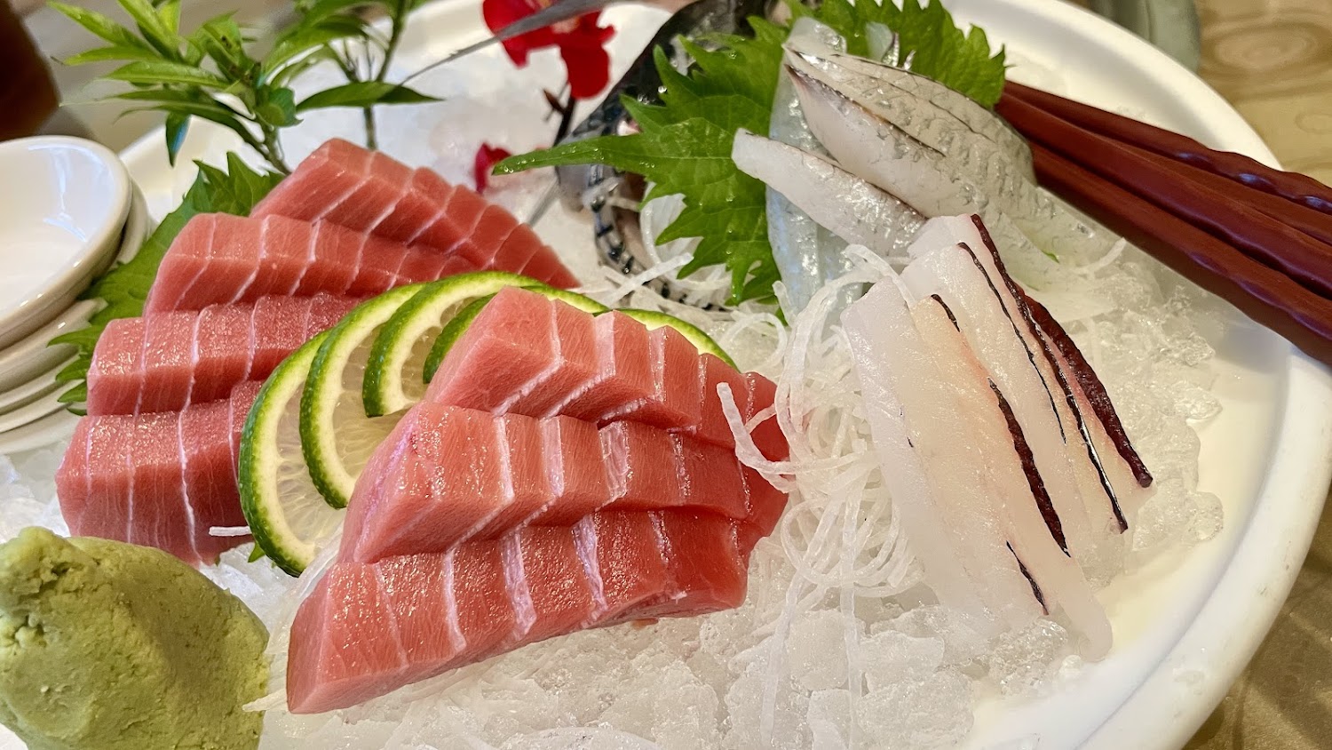 生魚片拼盤擺在碎冰上，附檸檬、蘿蔔絲與芥末。