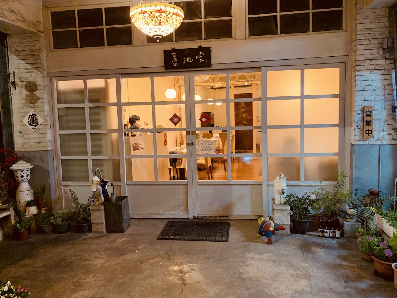 溫馨老屋店面外觀，有玻璃門窗、盆栽與明亮燈光。