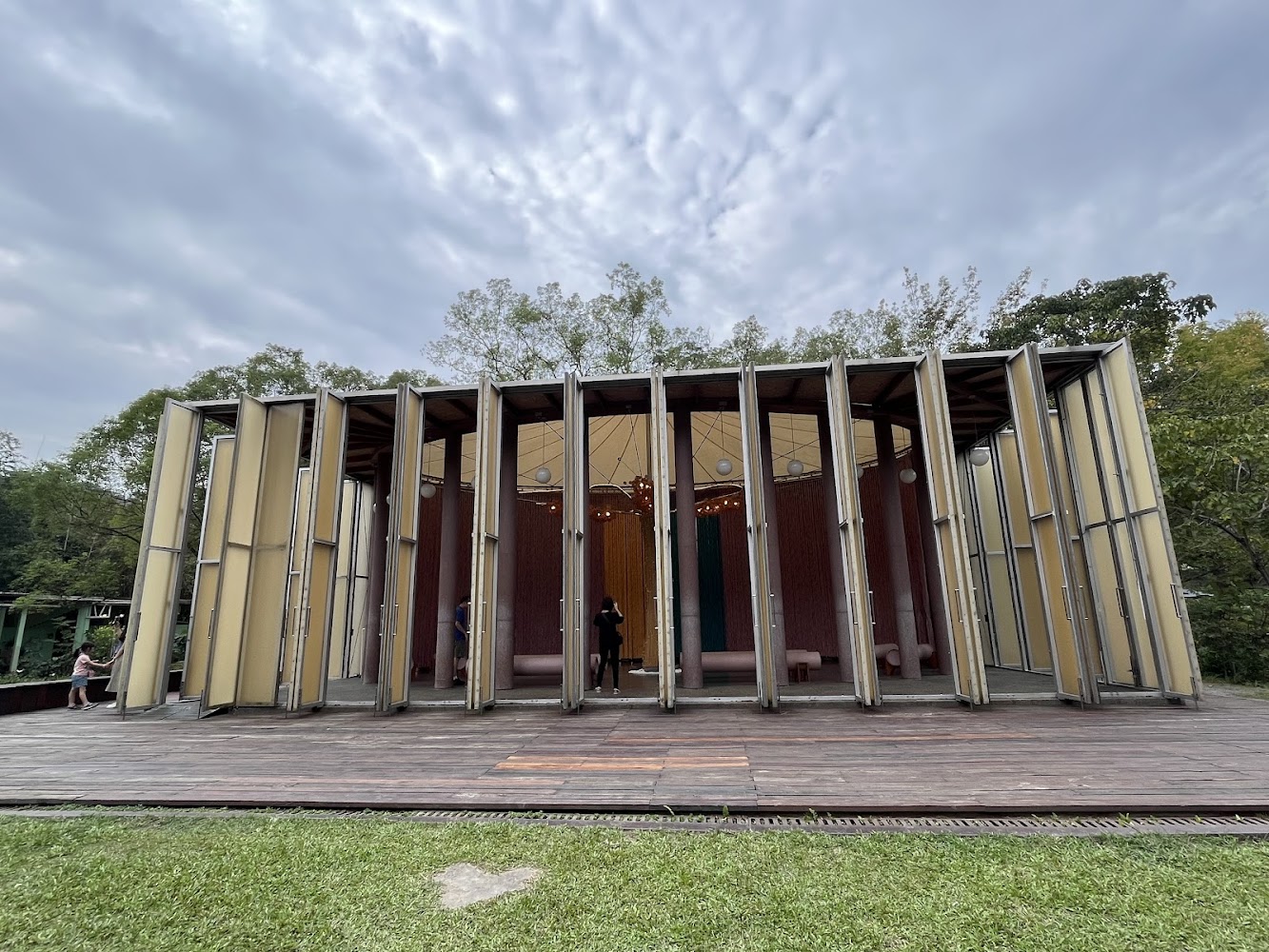 現代建築,外型呈現多面鋼構與玻璃結構,坐落於綠地與樹林間