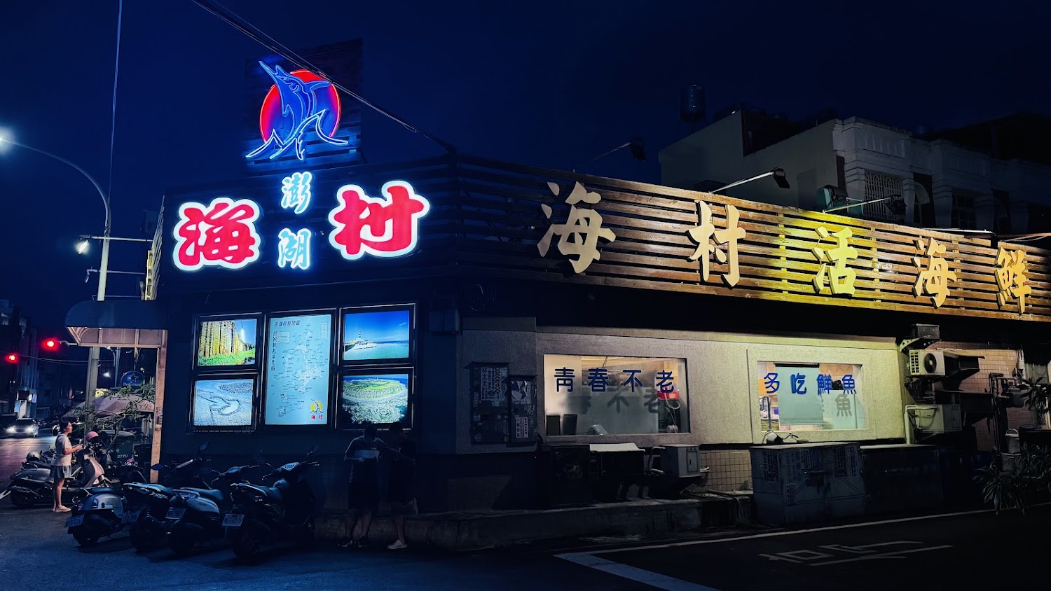 夜間海鮮餐廳外觀，霓虹燈招牌明亮顯眼。