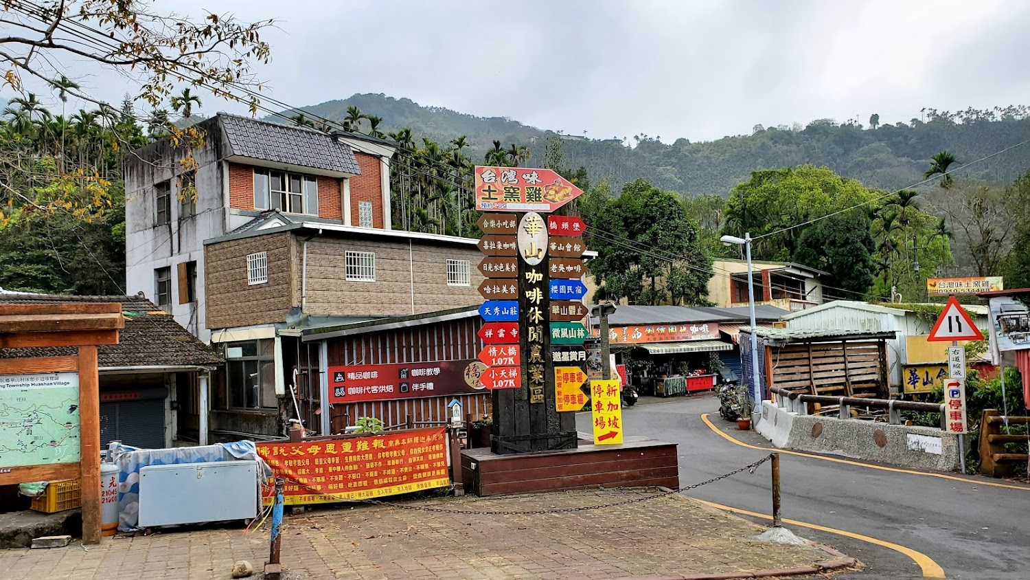 位於山區的村莊入口,有指示路牌標示咖啡區、民宿、停車場和當地特產