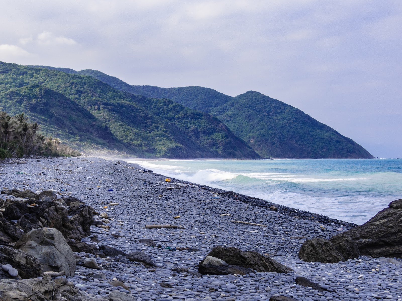 阿塱壹古道礫石灘浪花拍打，遠方山巒層疊