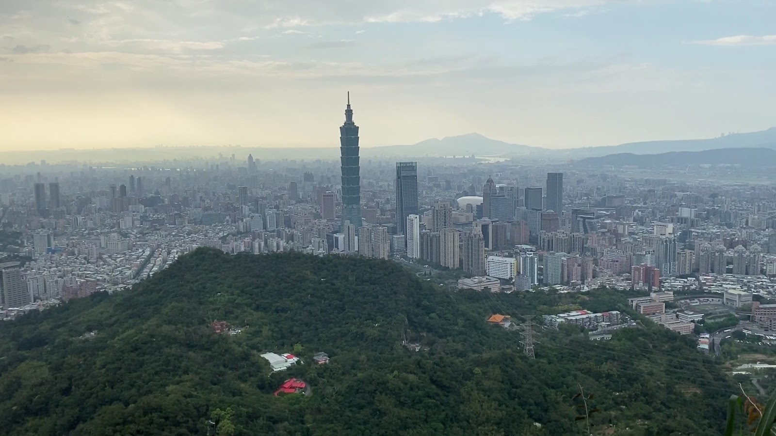 九五峰山頂近黃昏視角，台北101與城市剪影染上暖色光線