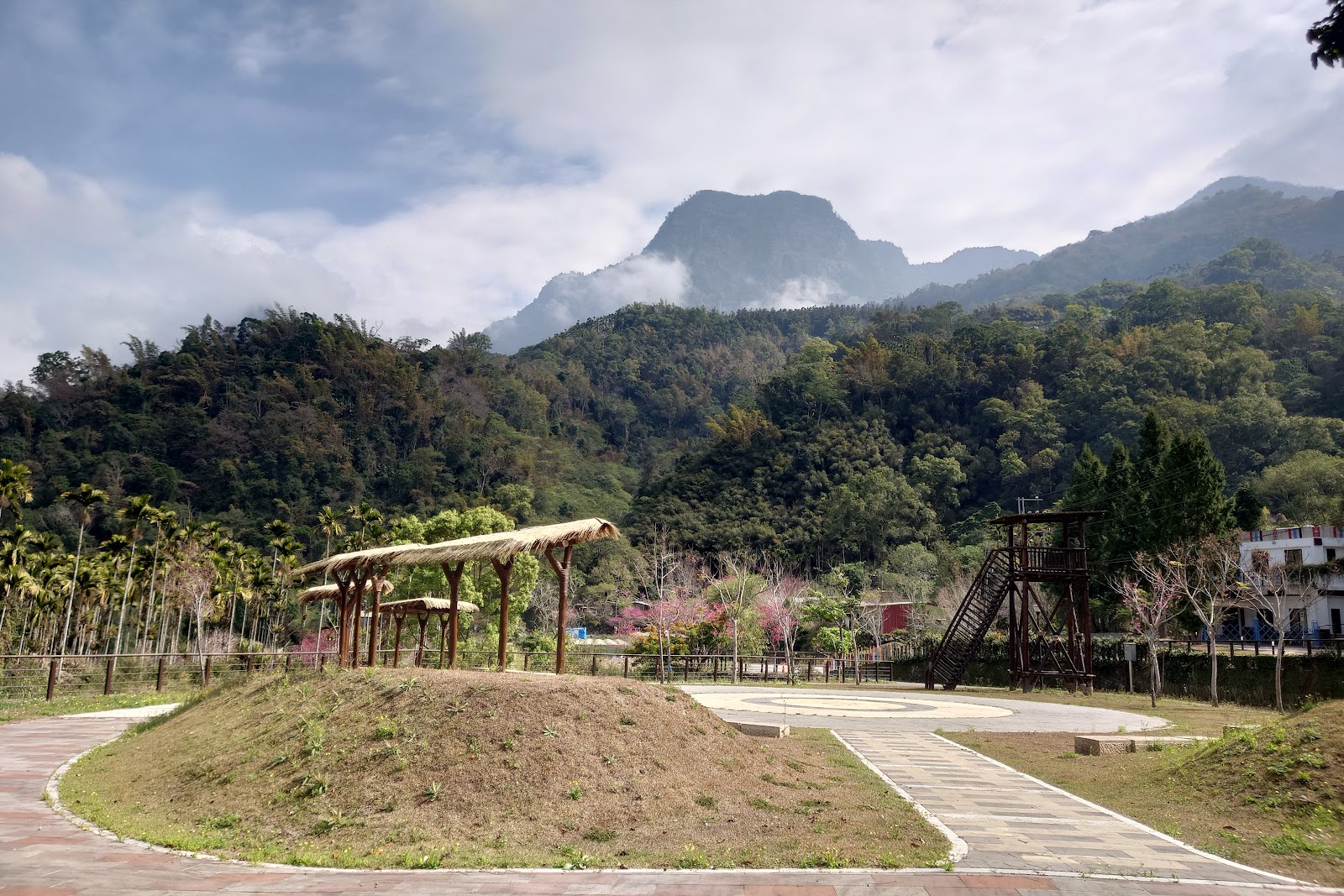 來吉文化廣場茅草涼亭與廣場地景，遠方大塔山雲霧繚繞