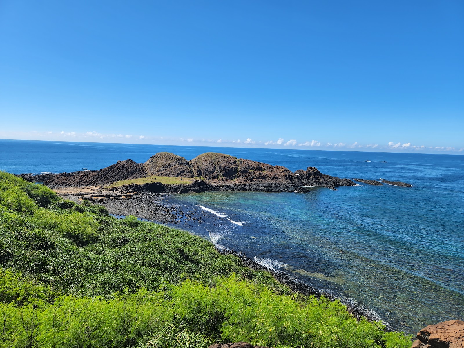 澎湖七美望夫石空拍海灣礁石景觀翠綠灌木草坡玄武岩礁石碧藍海水