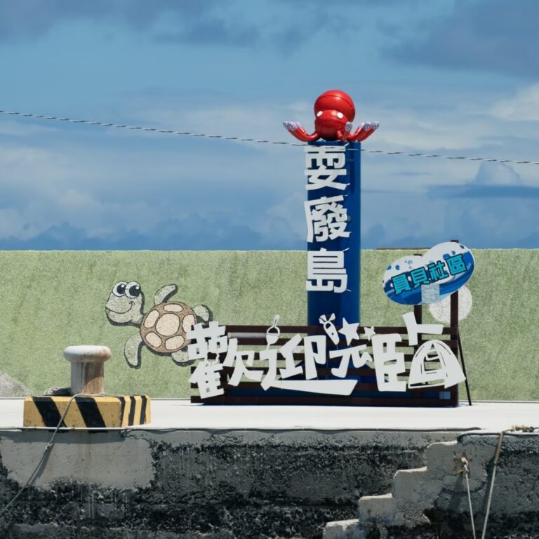 澎湖員貝嶼草綠山丘與玄武岩海崖，藍色海面環繞的離島景觀