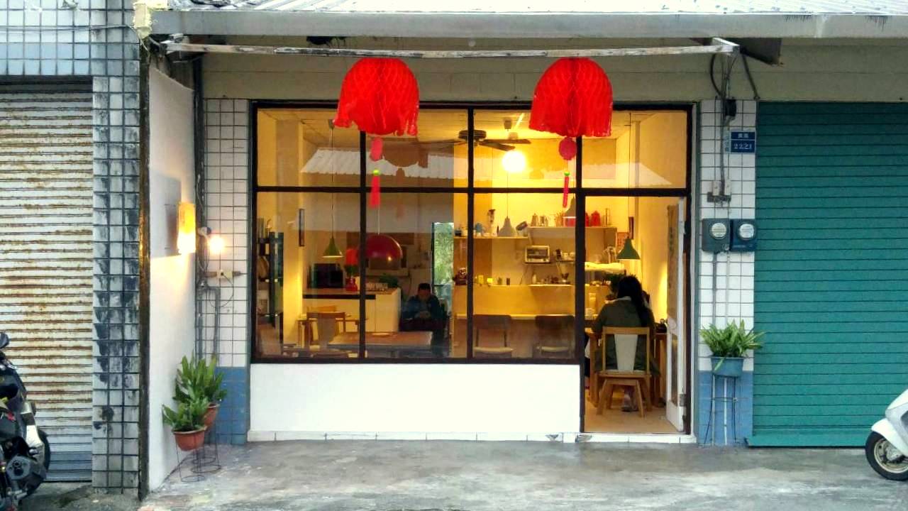 台東長濱巨大少年咖啡店落地玻璃窗外觀，黃昏時分透出溫暖燈光，長濱鄉咖啡慢旅必訪