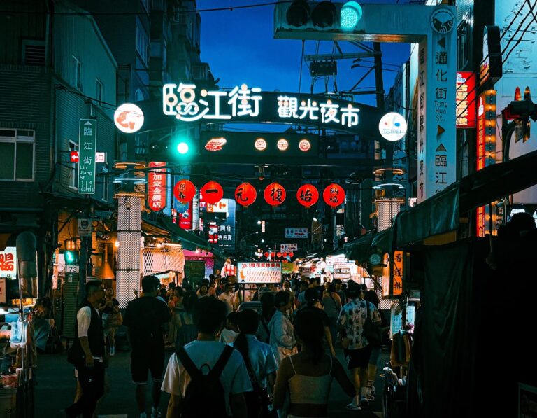 臨江街觀光夜市入口牌樓夜景，紅色燈籠與通化街霓虹招牌交織，人潮熙攘