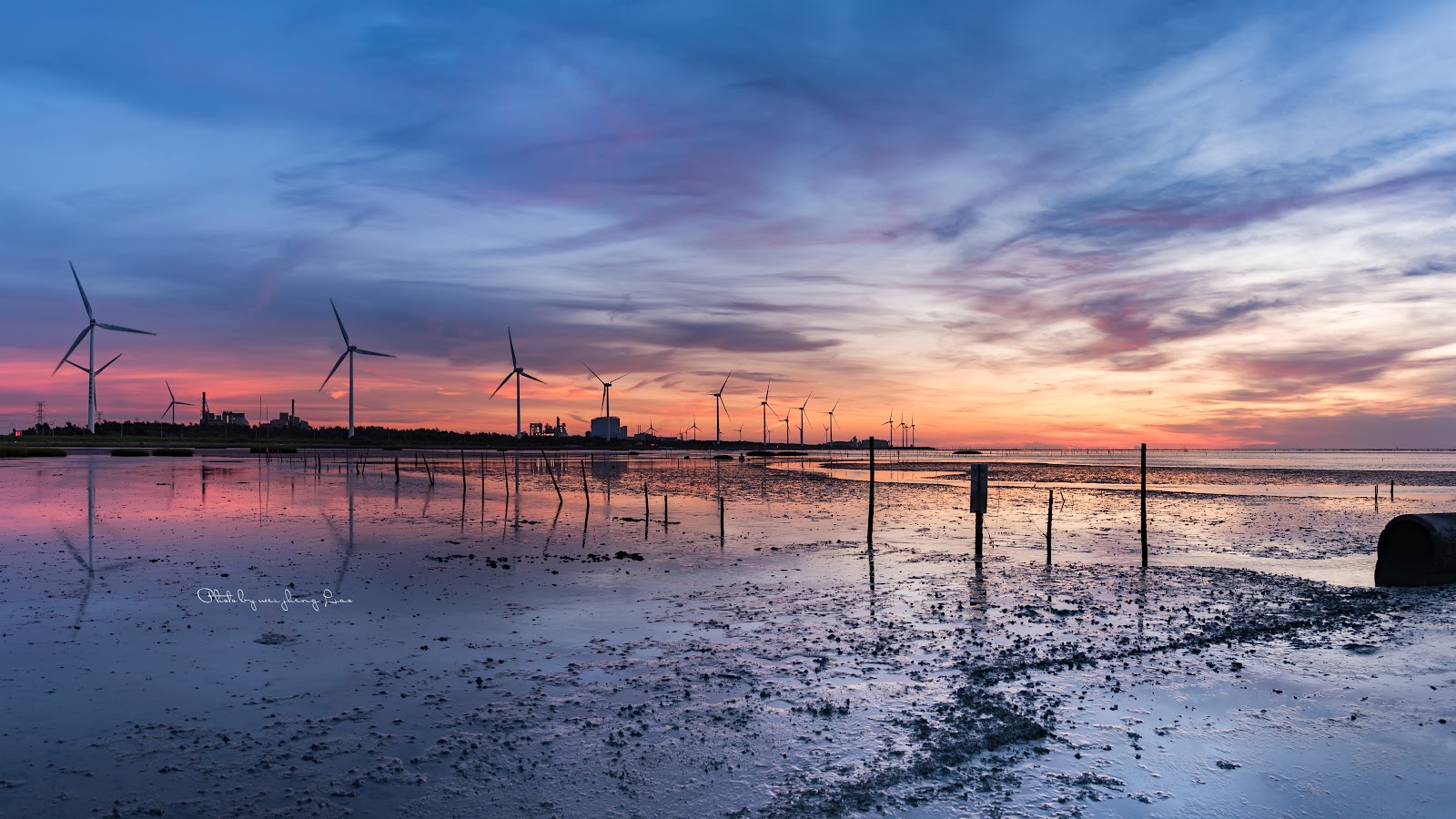 旭海漁港夕陽時分潮間帶景色，遠方風力發電機剪影