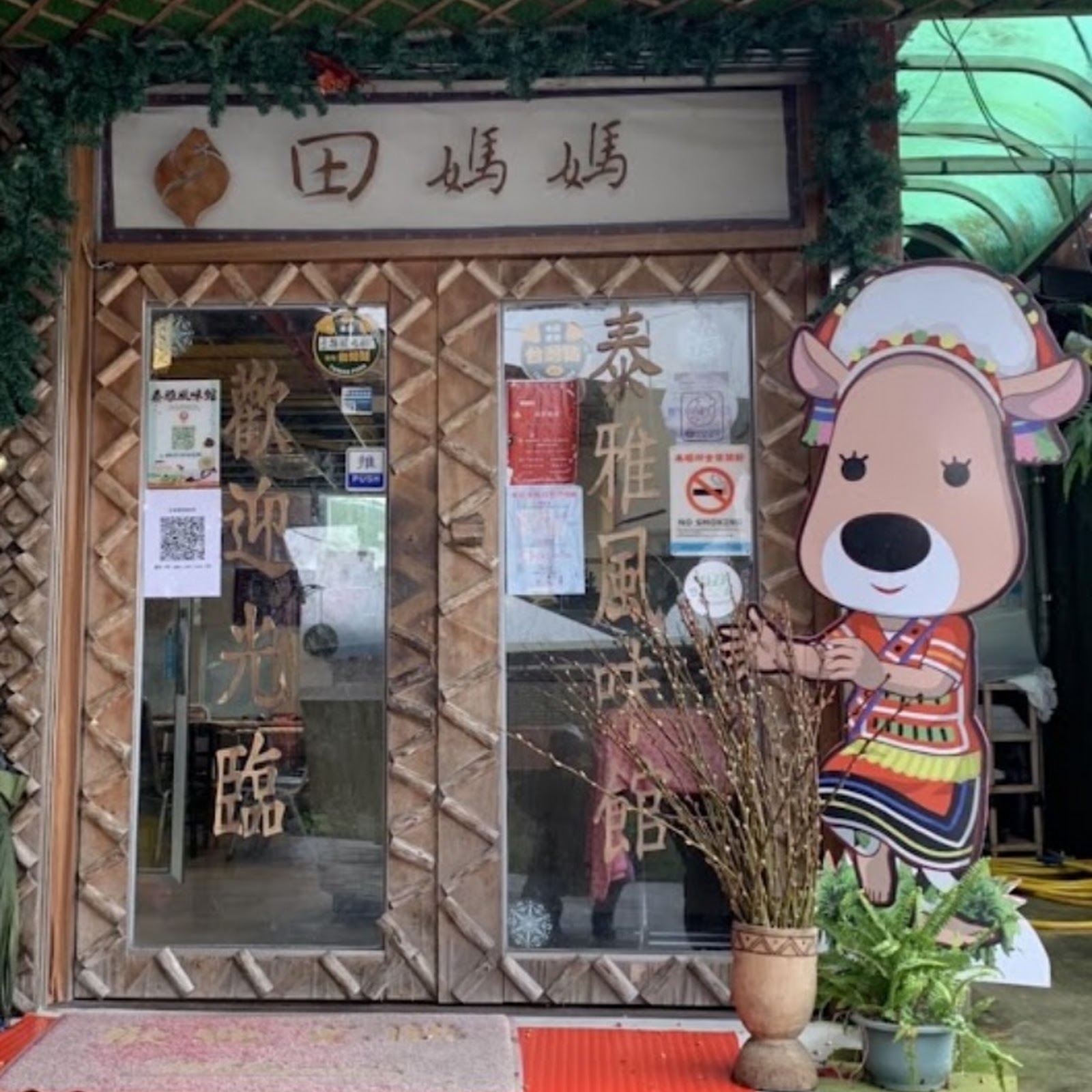 田媽媽泰雅風味館店門口，泰雅族圖騰吉祥物立牌與泰雅風味館招牌