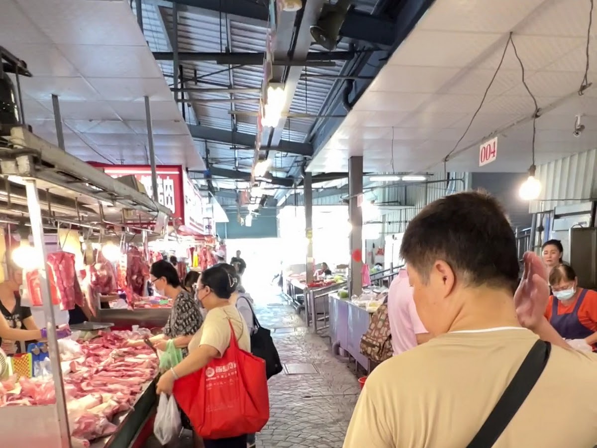 仁義市場走道內肉攤陳列,民眾提著購物袋採買