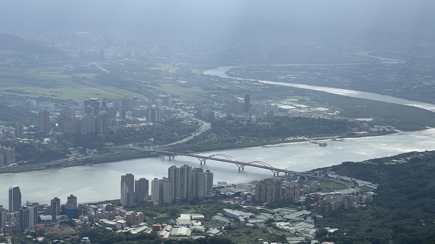 觀音山高處看紅色拱橋與河岸城市景色