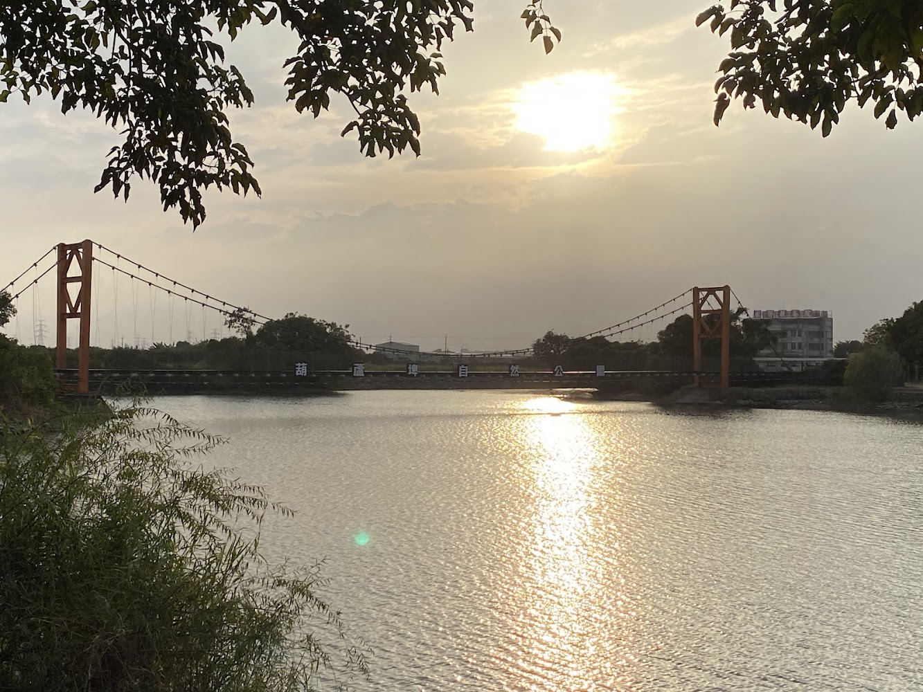 夕陽映照下的葫蘆埤吊橋與湖面倒影
