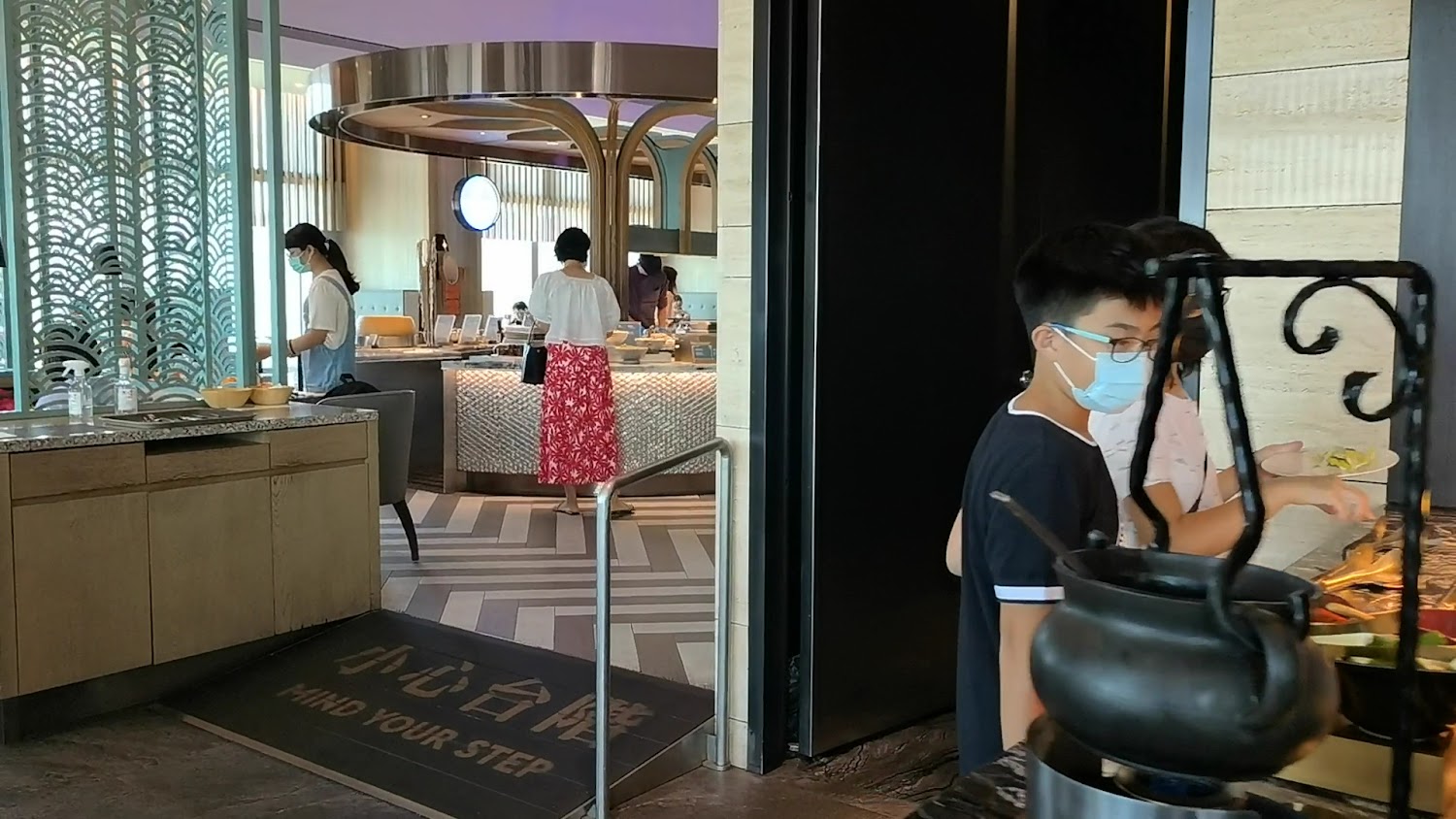 自助餐廳的取餐區，有多位顧客正在挑選食物，現場環境明亮整潔