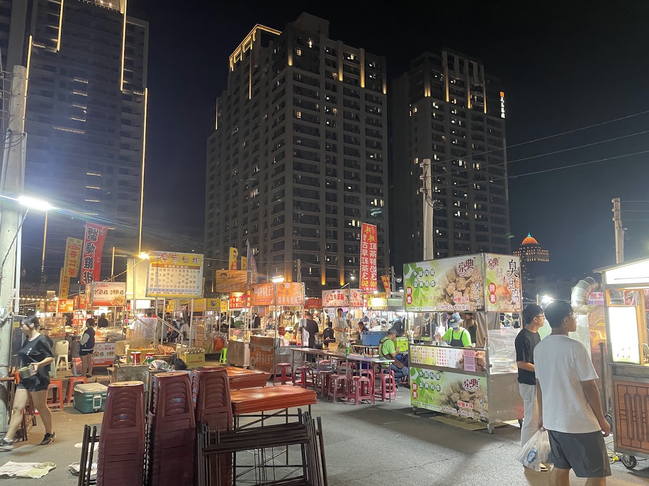 新永華夜市整體夜景與攤位人潮,高樓背景明顯
