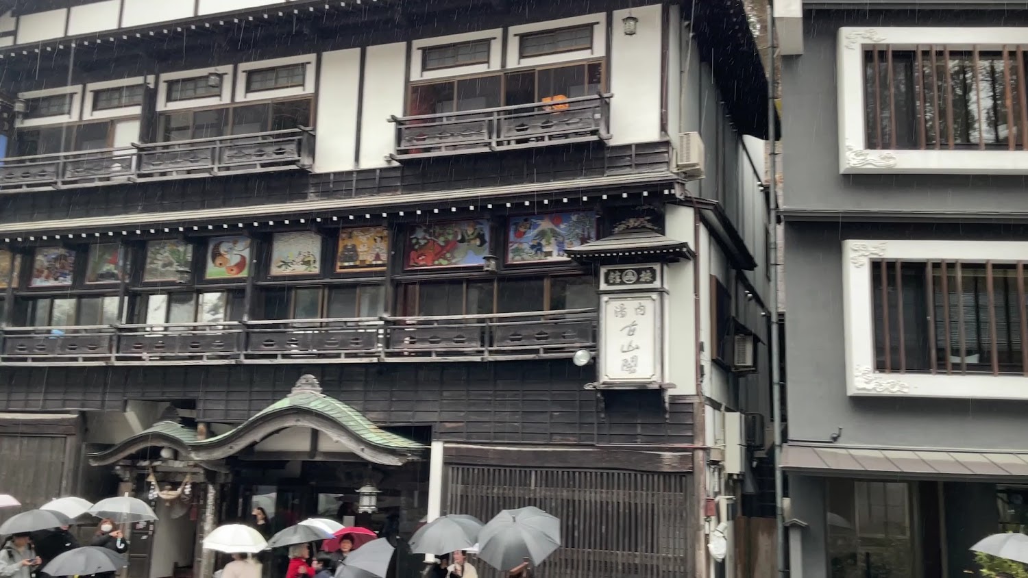 下雨天銀山溫泉傳統建築前遊客撐傘排隊