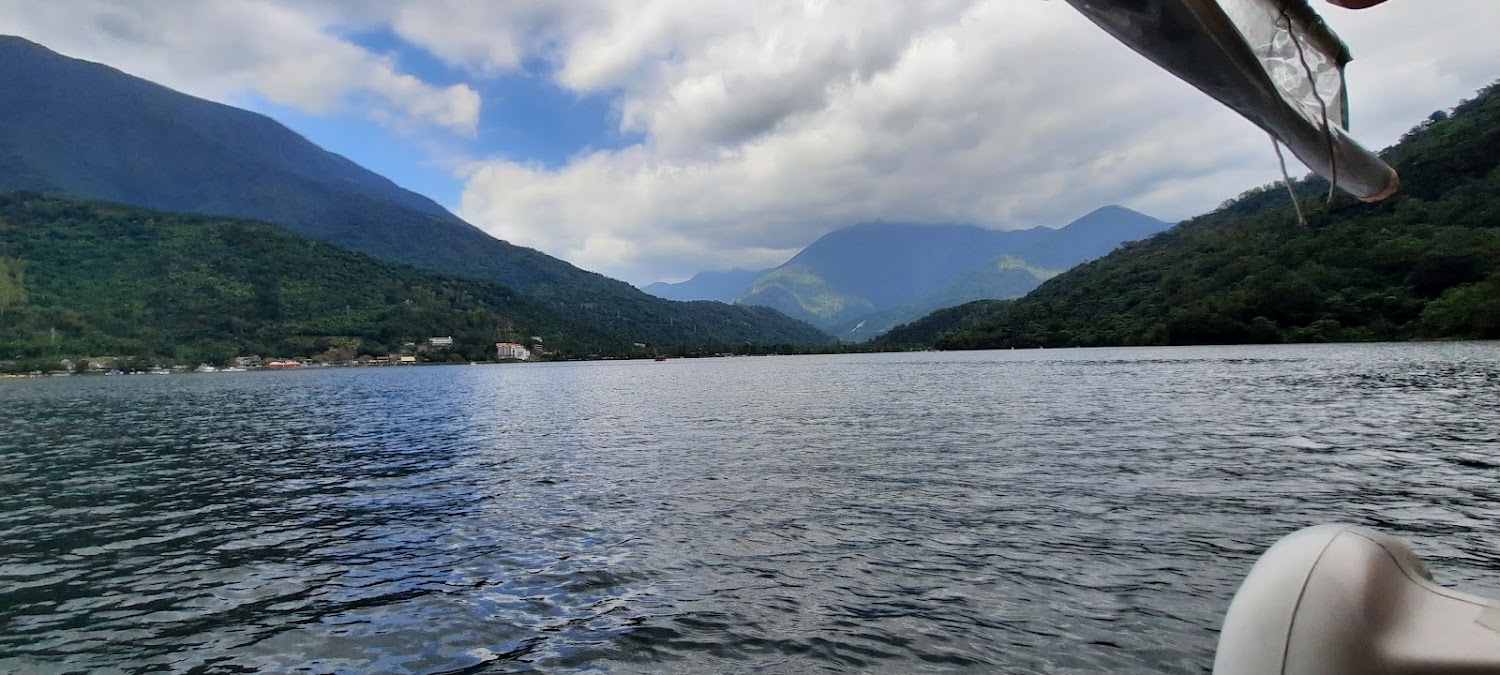 廣闊湖泊被翠綠高山環繞，遠方有雲霧與藍天