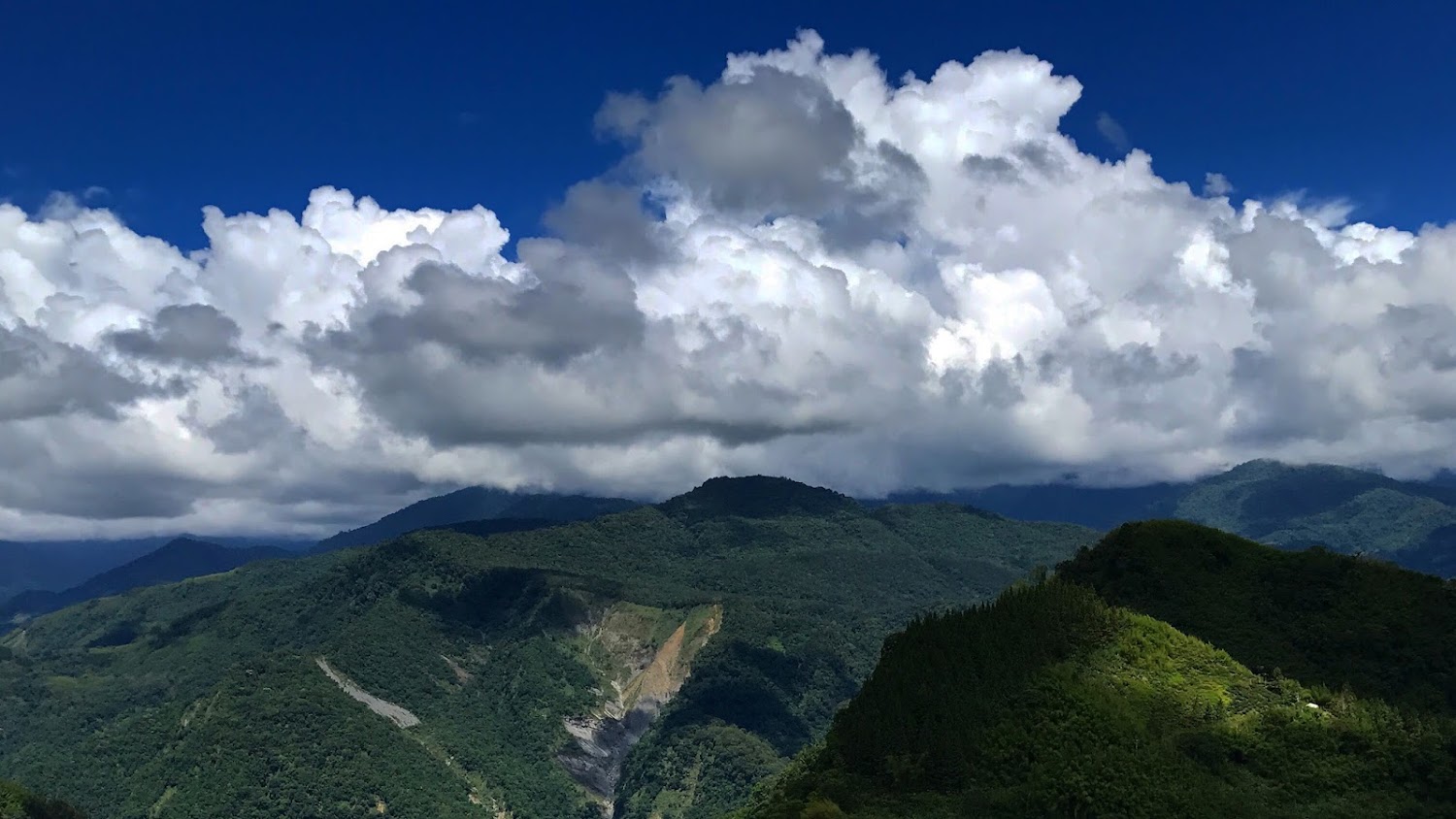 翠綠山林與層層山脈雲海藍天景致