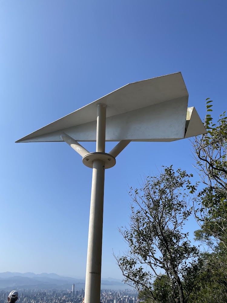 高處的大型紙飛機造型雕塑與城市山景