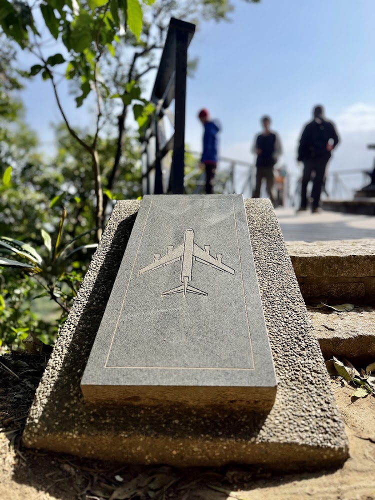 刻有飛機圖案的石碑與後方觀景台遊客