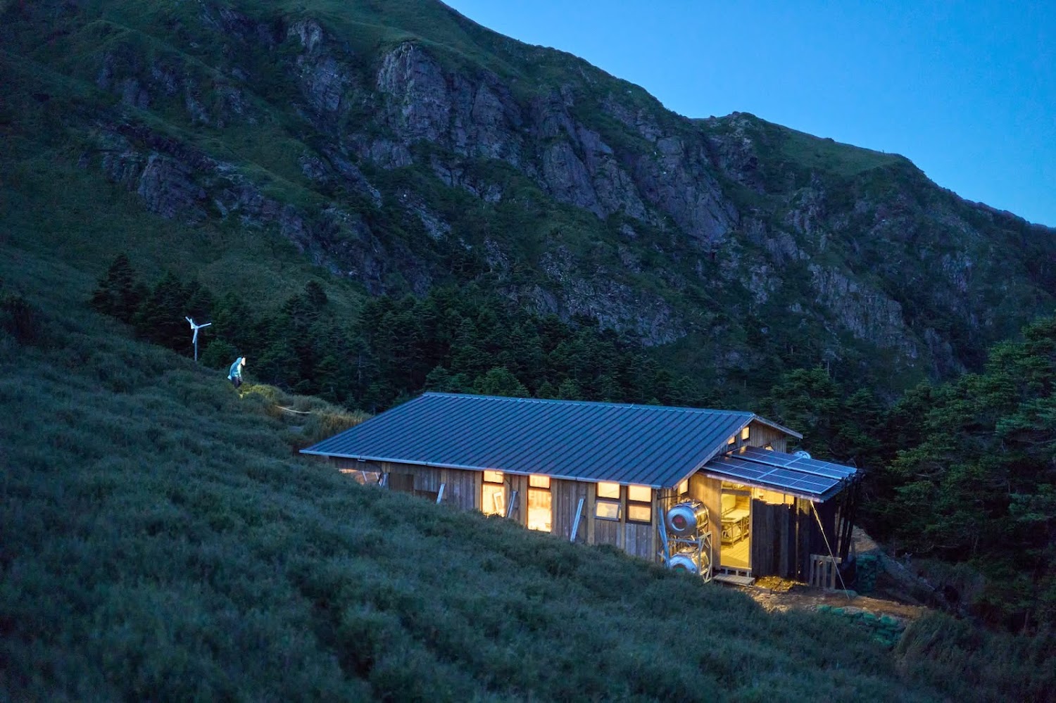 夜間亮燈的山屋與高山背景