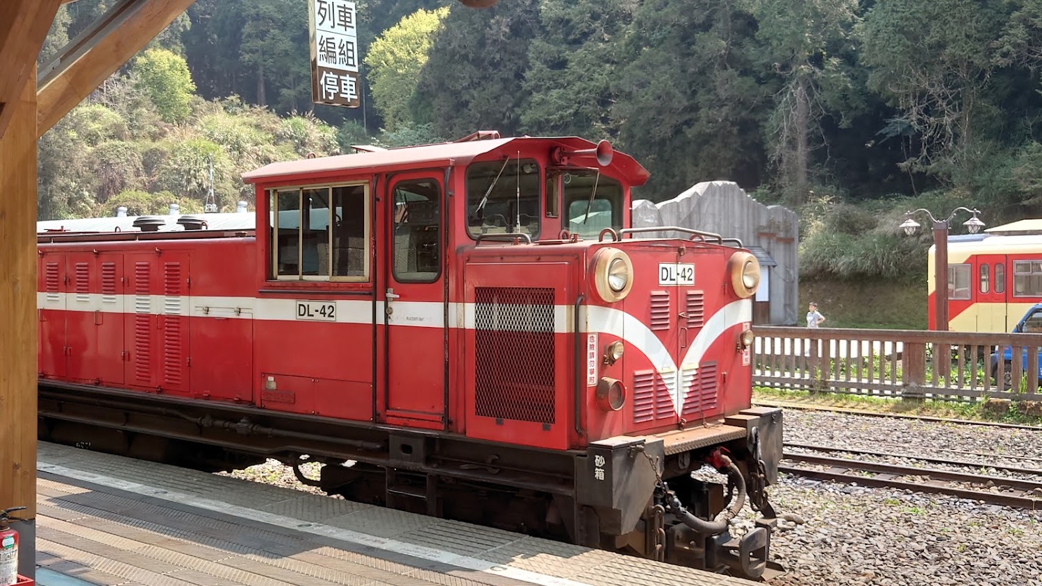 紅色窄軌火車停在山區車站月台旁