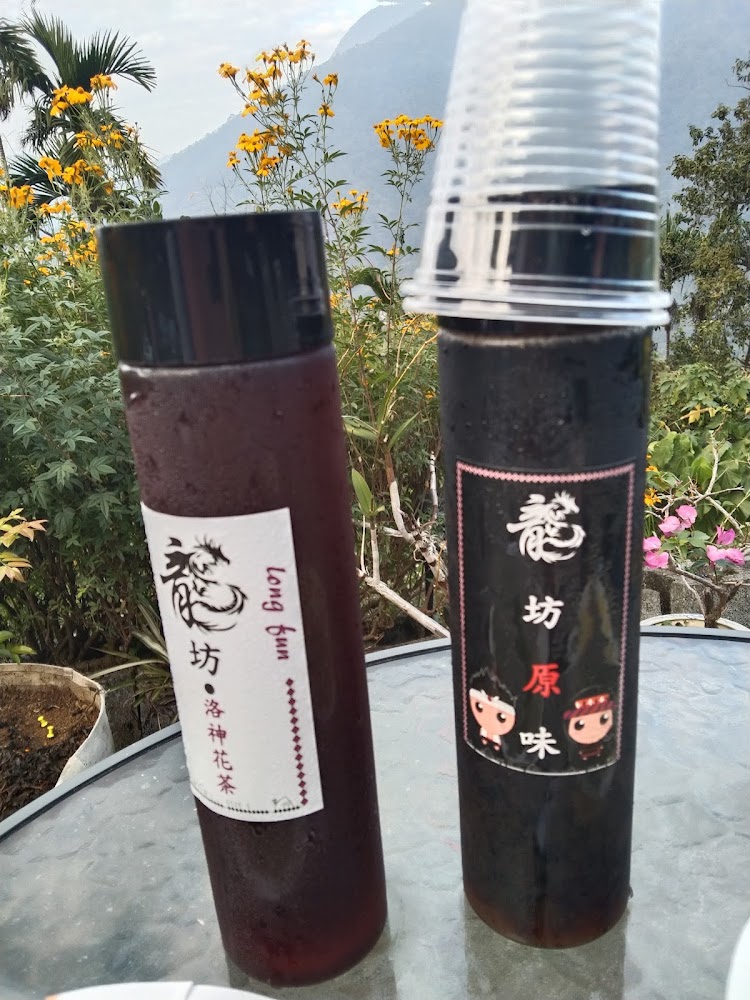 龍坊原味自家飲品放在戶外桌面,背景可見山景與花草