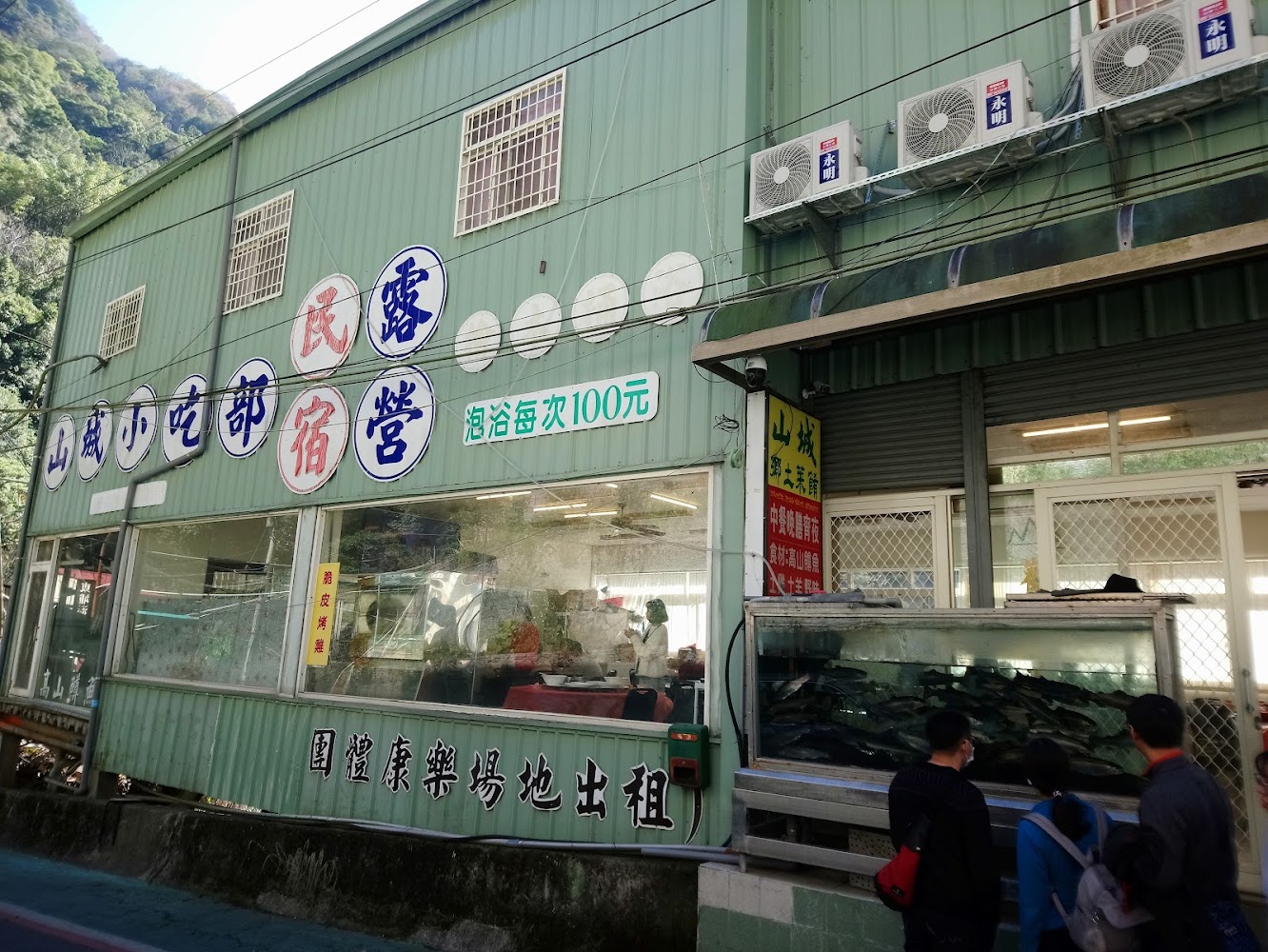 山城小吃外觀位於山區,門口有魚缸與多種招牌標示